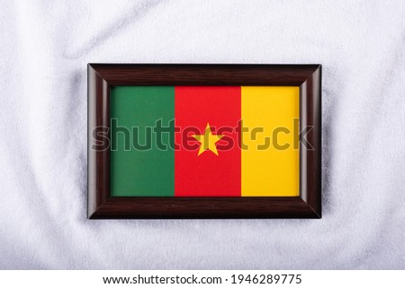 Cameroon flag in a realistic frame on white cloth background flat lay photo