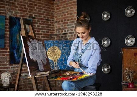 Young beautiful female artist painting still life with sunflower on canvas using oil paintings and art brush. Painter creating artwork in art studio. Relaxation, leisure, hobby, stress management