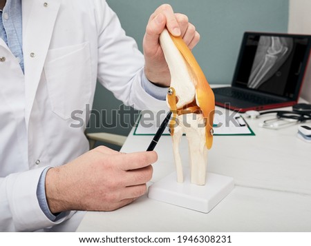 Human cruciate ligament injury treatment concept. Orthopedist showing to cruciate ligament in a knee-joint medical teaching model, close-up Royalty-Free Stock Photo #1946308231