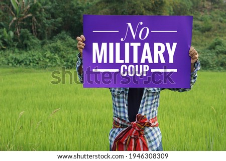 Text " No military coup" on paper sign hold by a man at green paddy field. Concept protesting for democracy and against the coup in Myanmar. Royalty-Free Stock Photo #1946308309