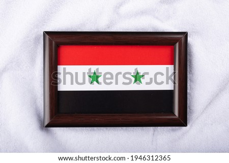 
Syria flag in a realistic frame on white cloth background flat lay photo