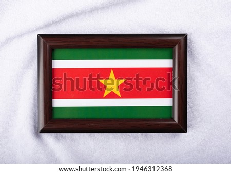 Suriname flag in a realistic frame on white cloth background flat lay photo