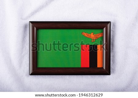 
Zambia flag in a realistic frame on white cloth background flat lay photo