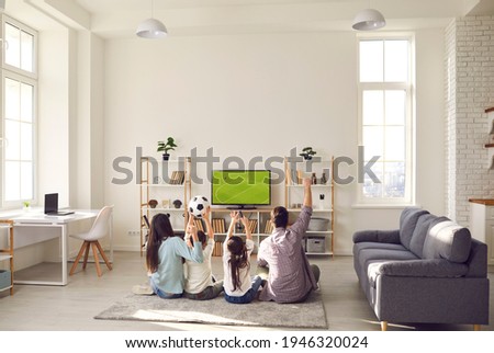 Football match, leisure and happy family sport fan pastime together. Excited parent with overjoyed children watching soccer game on tv sitting on floor carpet in living room at home. Rear view Royalty-Free Stock Photo #1946320024