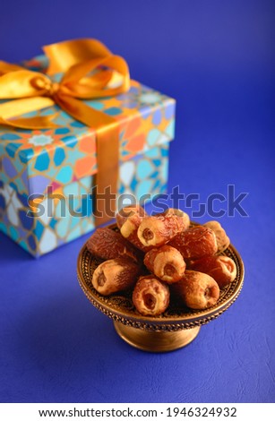 Gift box with Islamic pattern design and bowl of dates fruits. Royalty-Free Stock Photo #1946324932