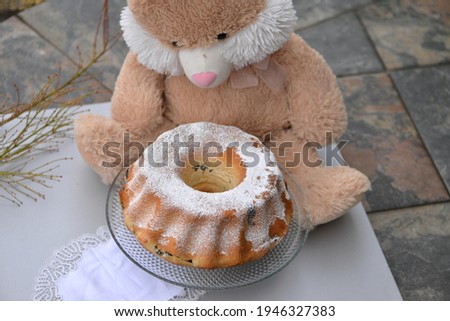 Home baked potica, traditional Slovenian Easter sweet bread roll stuffed with poppy seeds; Easter bunny holding a plate with Easter cake on the table