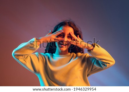 Smiling. Portrait of young happy funny beautiful girl posing isolated on gradient pink blue background in neon light. Concept of human emotion, facial expressions, youth culture. Copy space for ad.