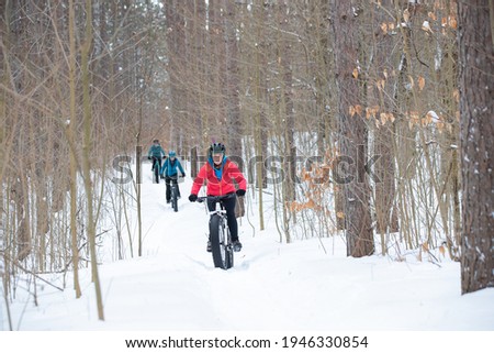 A group of attractive women ride their fat bikes on a trail in the snow.