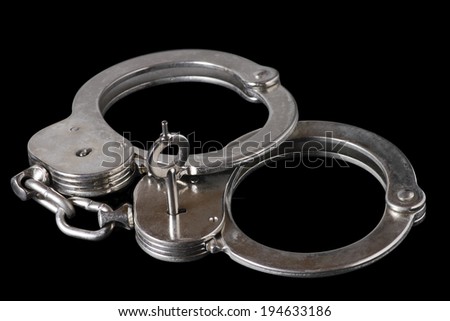 Metallic handcuffs. Used as a temporary restraining device, handcuffs are an essential part of any law enforcement agents rigging.  Royalty-Free Stock Photo #194633186
