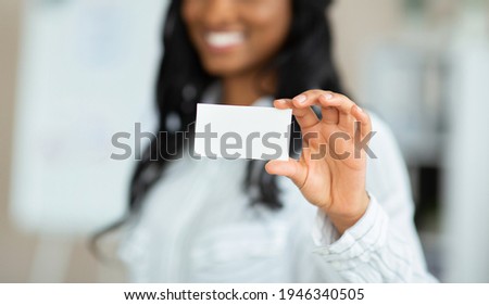 Cropped view of businesswoman demonstrating empty business card with mockup for design at office, selective focus. Female manager showing blank advertising card with space for your ad
