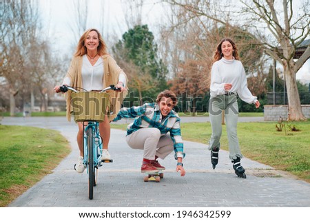 Playing sports as a family while we celebrate Mother's Day. The son on a skate, the sister on a roller skate and the mother on a bicycle.