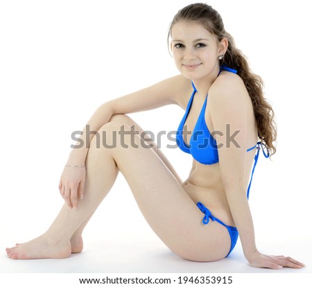 Slim and fit teenage girl wearing a blue bikini in studio isolated on white