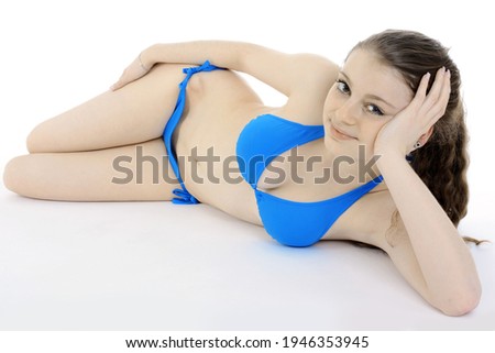 Beautiful slim teenage girl wearing a blue bikini in studio isolated on white