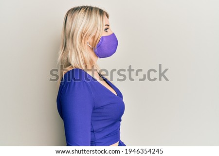 Young caucasian woman wearing covid-19 protection mask looking to side, relax profile pose with natural face with confident smile. 