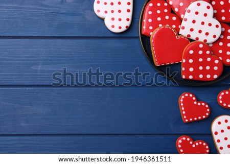 Glazed heart shaped cookies on blue wooden table, flat lay. Space for text
