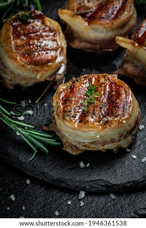 Medallions steaks from the beef tenderloin covered bacon on Dark background. Top view vertical image.