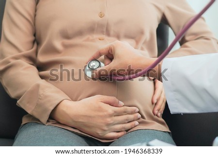 Doctor using stethoscope listening baby in pregnant belly at hospital Royalty-Free Stock Photo #1946368339