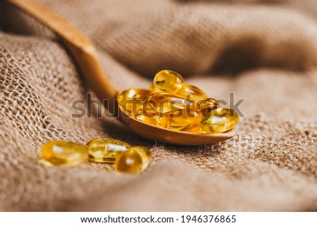 Vitamin complex omega 3,6,9. Fish oil capsules on a wooden spoon. Fish oil pills, tablets on the burlap. Copy space Royalty-Free Stock Photo #1946376865