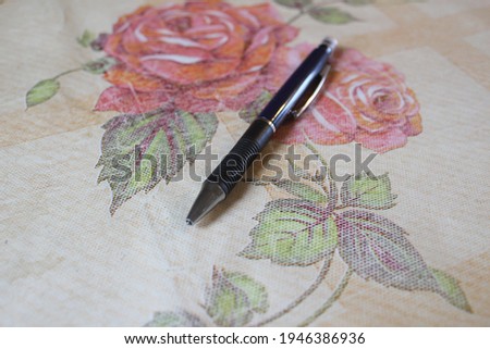 a pen on an old table with red roses with an oilcloth buy it you will not regret it