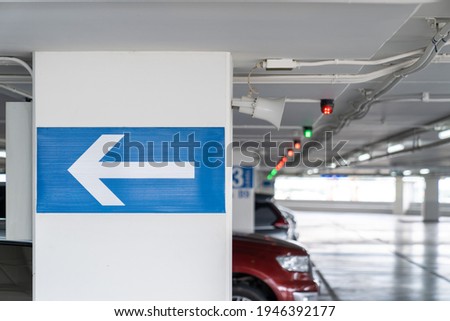 white arrow Signage on the indoor carparking pole, tell driver which way to go and location in parking lot.