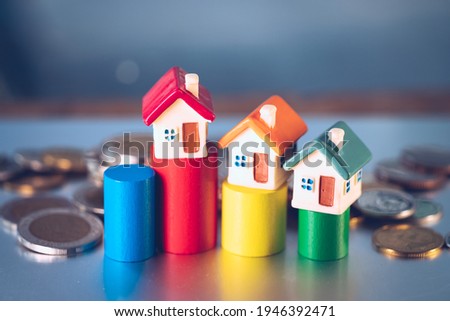 High angle view miniature house on colorful wooden block with stack coins using as property real estate, business and family concept
