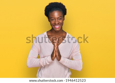 Young african american girl wearing casual clothes praying with hands together asking for forgiveness smiling confident. 