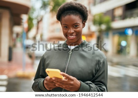 Young african american girl smiling happy using smartphone at the city