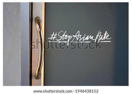 English texts ‘#StopAsianHate ‘ on glass door, concept for calling all people to stop hating and harassing Asian people, selective focus on texts.