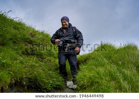 Professional nature photographer hiking into the mountains in a rainy day