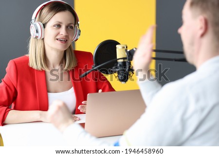 Young woman in headphones interviewing man on radio station