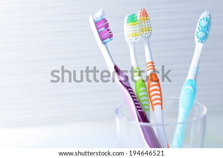 Toothbrushes in glass on table on light background Royalty-Free Stock Photo #194646521