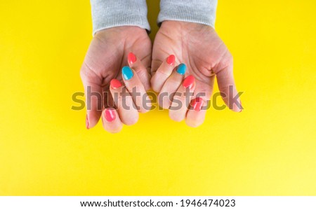 beautiful Woman nails on yellow background. Manicure concept. Female hands with pink and blue manicure. Concept of nails design. Blank space for your text