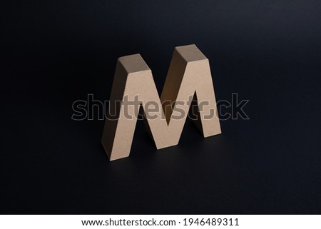 Letter M made in cardboard on black background elegant letter m