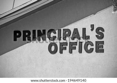 A sign on the side of a school building shows where the principal's office is located.