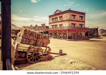 Town square as a western movie set. Spaghetti western. Cart loaded with straw bales. Travel concept Royalty-Free Stock Photo #1946491594