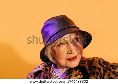 Woman with red lips squints in the sun while posing at the studio