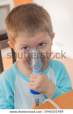 Little boy using nebulizer during inhaling therapy. Little boy making inhalation with nebulizer at home. Close up portrait of boy taking inhalation for asthma prevention.