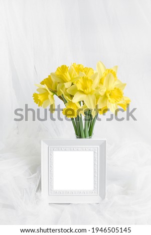 mockup of spring postcard, invitation, banner. bouquet of beautiful yellow daffodils and white photo frame with place for text. minimalistic holiday concept - mothers day, easter.