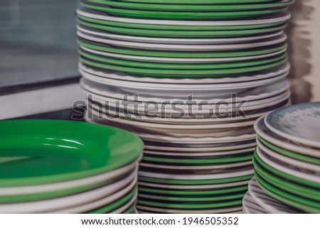 Close-up shot high stack storage of melamine plastic round white green clean flat plates after washing. Is this Kitchen dishes utensils bad, harmful to eat or safe. Cheap price or health compromise