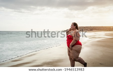 Happy plus size woman having fun walking on tropical beach during summer time - Curvy confident people lifestyle concept