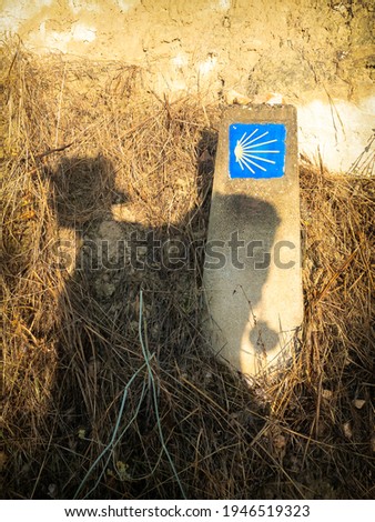 Shadow of a Pilgrim and a Camino de Santiago Way Marker with the Shell and Yellow Arrow, outside Torres del Rio