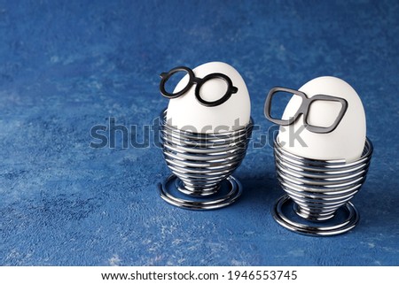White eggs of a chicken farm on a blue background. Glasses and breakfast. Easter creative holiday concept. Copy space. Interesting food