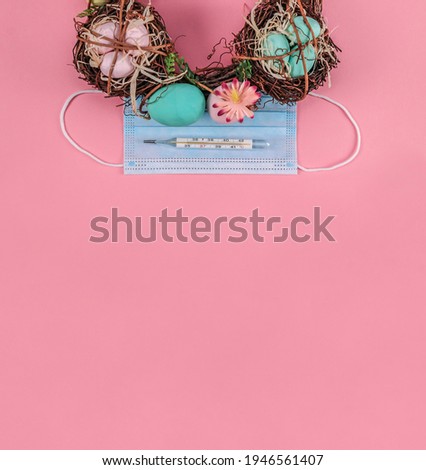 Easter wreath with nests, eggs, mask and thermometer lie on a pink background with space for your text from below, close-up top view.