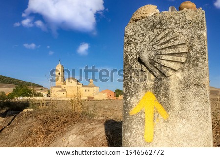 Way Marker Stone Post with Yellow Arrow Pilgrimage Symbol and View of Church in Castrojeriz on the Way of St James Pilgrim Trail Camino de Santiago