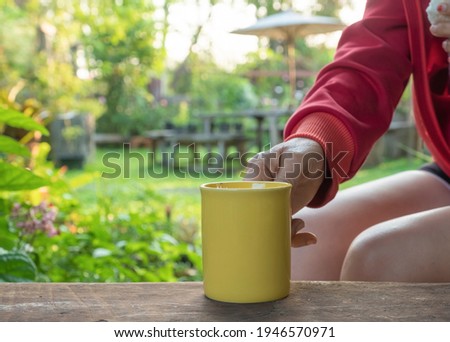 social distancing concept picture of a yellow cup of coffee on wooden table while having morning coffee far away from the people for safety. 