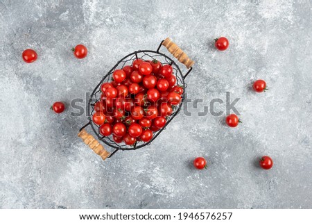 Cherry tomatoes in a metallic basket on marble background