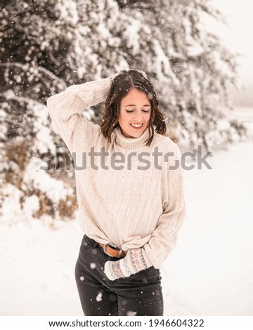 Portrait of young beautiful caucasian woman enjoying the snow in cold winter scenery