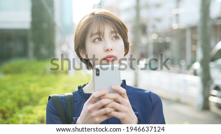 Young asian woman using a smart phone on the street.