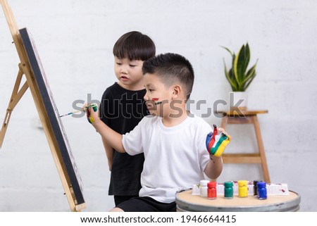 Happy two little Asian boy painting with watercolor on canvas standing in white room at home, creative young artist at work. Kids paint. Children draw.