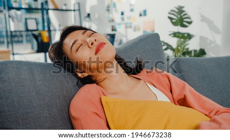Beautiful asian lady feel relax lay down on sofa with pillow at home. Stay home, Take a break from work, Relax in comfort zone at home, Get some rest at home, keep distance, covid quarantine concept.